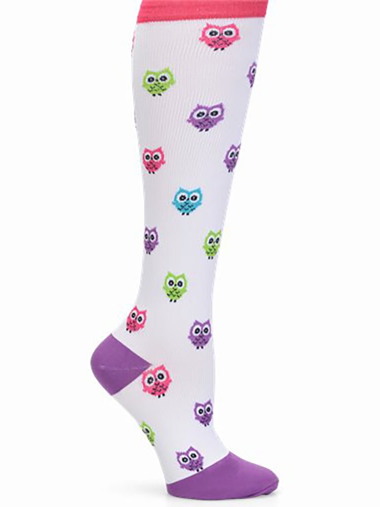The NurseMates Women's Wide Calf Compression Socks in "Owls" featuring a cute print featuring cartoon owls in shades of pink, purple and green on a white background.