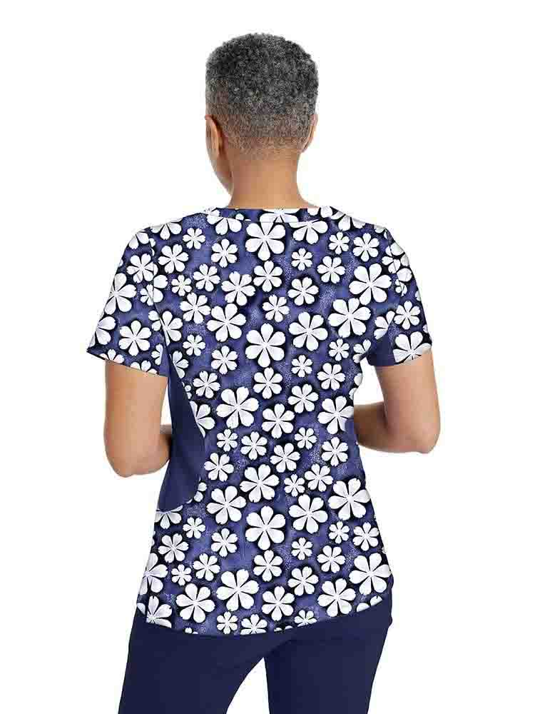A registered nurse wearing a Premiere by Healing Hands Women's Jessi Print Top in "Just Daisies" featuring a curved hemline.