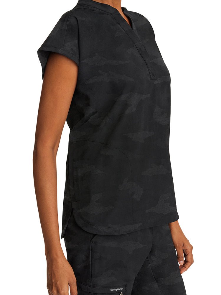 A young female LPN wearing a Purple Label Women's Journey Camo Top in Black size XS featuring a total of 2 pockets.