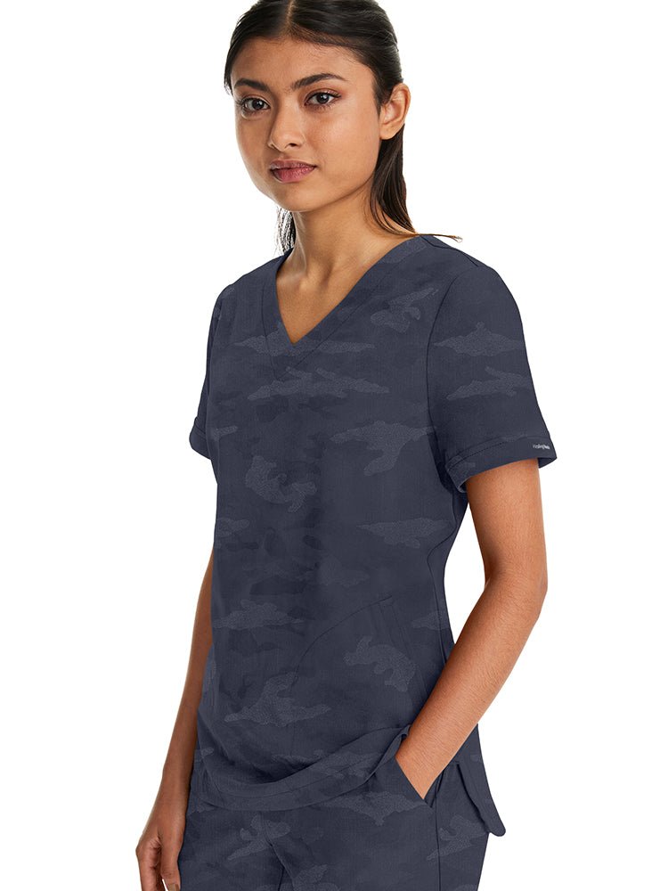 Young nurse wearing a Purple Label Women's Joy Camo Top in Pewter with 2 welt pockets on each side.