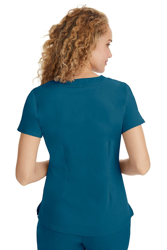 A young LPN wearing a Purple Label Women's Jane V-Neck Scrub Top in Caribbean featuring a medium center back length of 26.5".