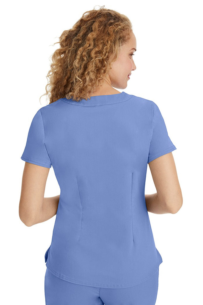 A young LPN wearing a Purple Label Women's Jane V-Neck Scrub Top in Ceil featuring a medium center back length of 26.5".