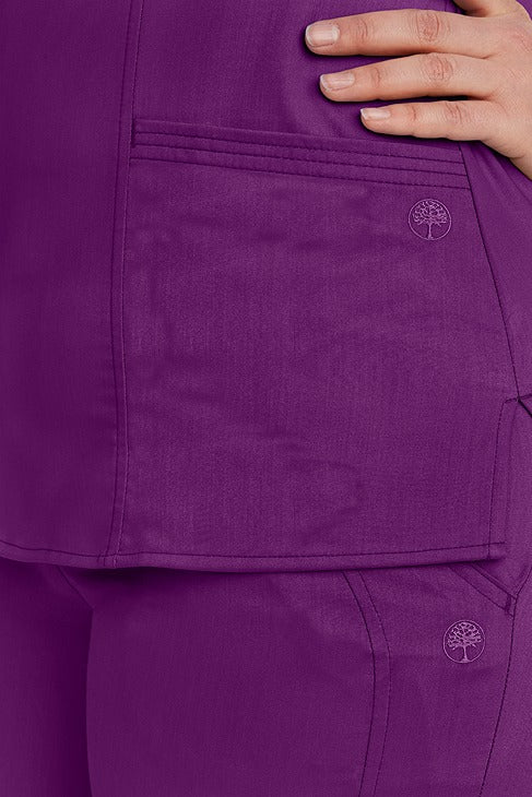 A young female RN wearing a Purple Label Women's Jordan Crossover Top in Eggplant featuring 2 front patch pockets.