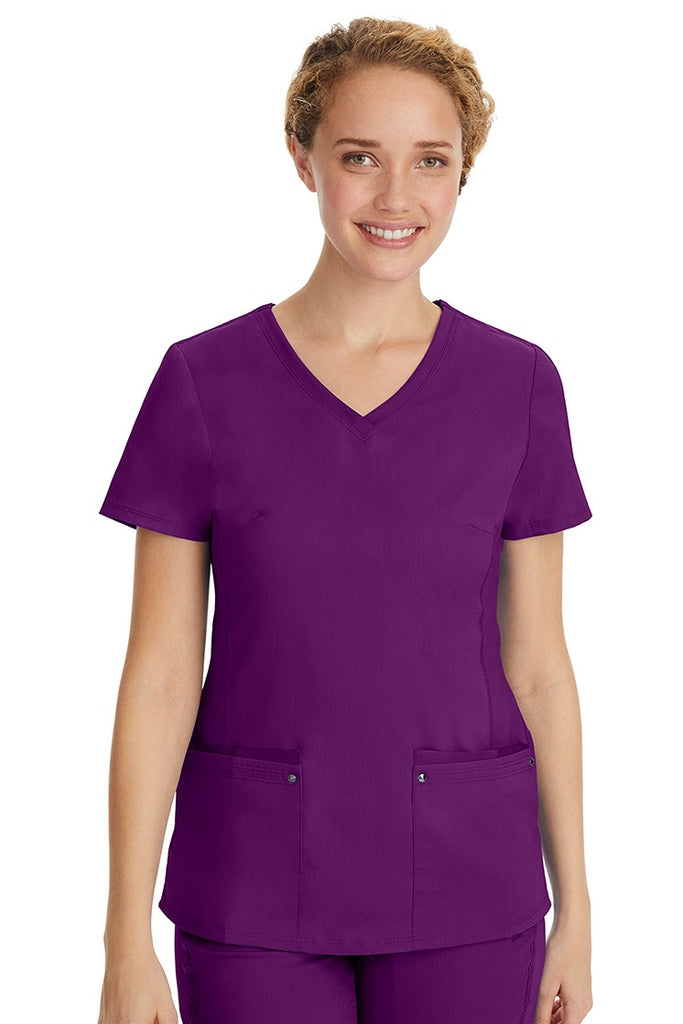 A young LPN wearing a Purple Label Women's Juliet Yoga Scrub Top in Eggplant featuring 2 front patch pockets.