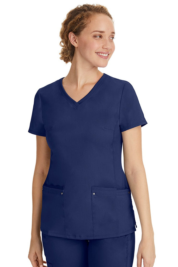 A female healthcare professional wearing a Women's Juliet Yoga Scrub Top from Purple Label in Navy featuring a side stretch panels.