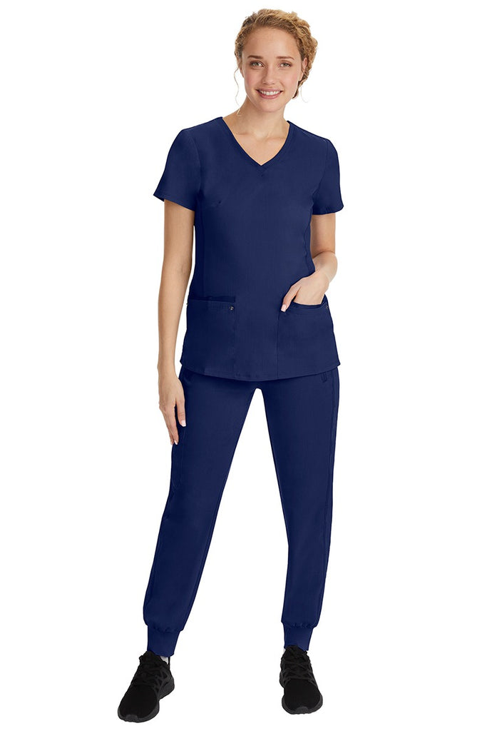 A young female nurse wearing a Purple Label Women's Juliet Yoga Scrub Top by Healing Hands in Navy featuring a v-neckline.