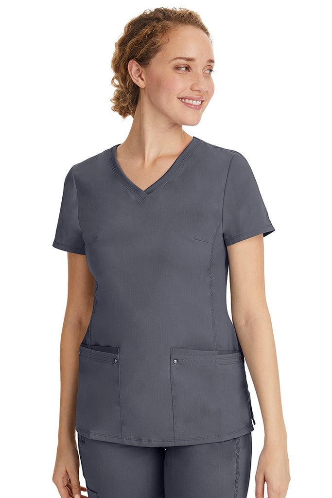 A female healthcare professional wearing a Women's Juliet Yoga Scrub Top from Purple Label in Pewter featuring a side stretch panels.