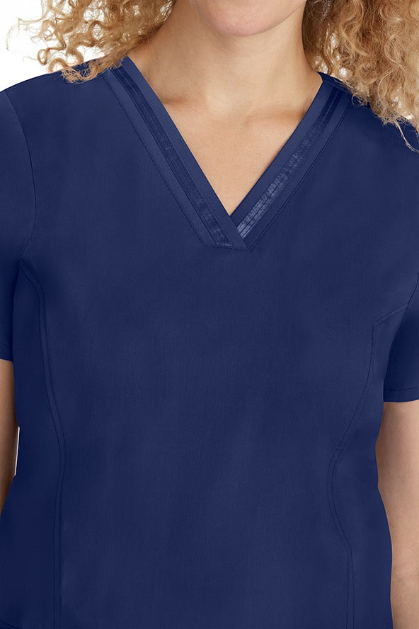 A young lady CNA wearing a Purple Label Women's Jasmin Fashion V-neck Scrub Top in Navy featuring a super comfortable stretch fabric made of 96% polyester & 6% spandex.