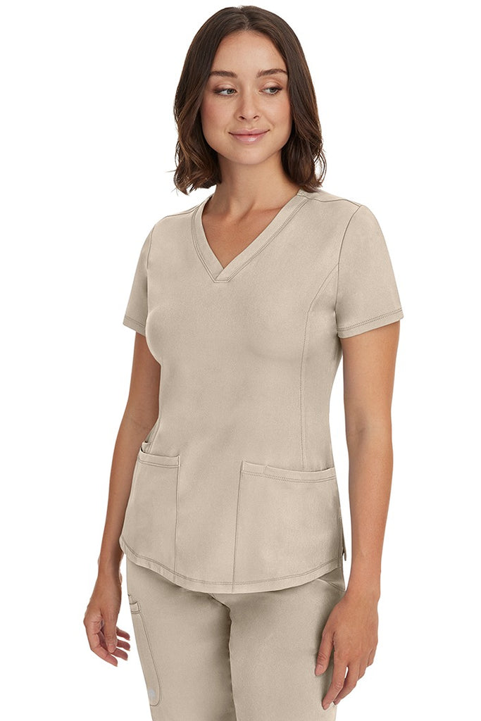 A young female Medical Records Director wearing an HH-Works Women's Monica Multi-Pocket Scrub Top in Khaki size Small featuring a total of 4 pockets.