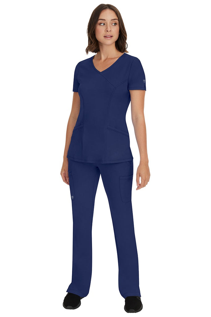 A female Nurse Practitioner wearing an HH-Works Women's Madison Mock Wrap Scrub Top in Navy featuring a super comfortable fabric made of 91% polyester & 9% spandex.