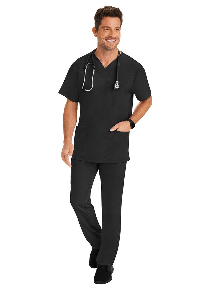 A young male Home Care Registered Nurse wearing an HH-Works Men's Matthew V-Neck Scrub Top in Black featuring a fade resistant fabric to ensure a long-lasting comfortable fit.