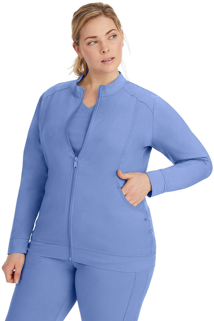 A young LPN wearing a Purple Label Women's Dakota Zip Up Scrub Jacket in Ceil featuring a super comfortable fabric made of 77% Polyester/20% Rayon/3% Spandex.
