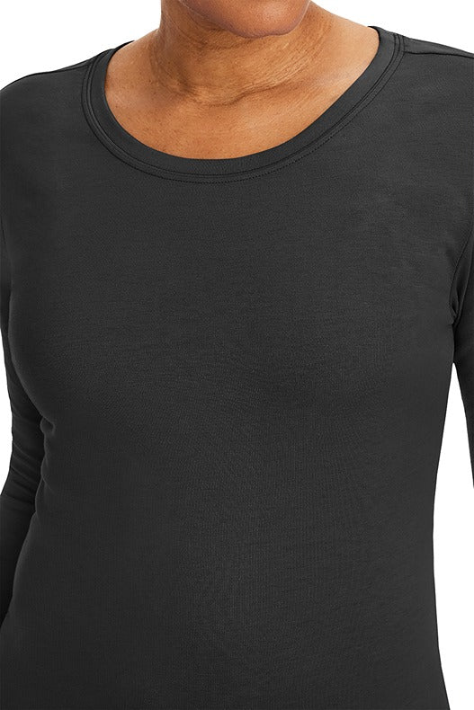 A lady nurse practitioner wearing a Purple Label Women's Melissa Long Sleeve T-Shirt from Healing Hands in Black featuring a super comfortable fabric blend that resists wrinkles, shrinking, and fading better than traditional cotton scrubs. 