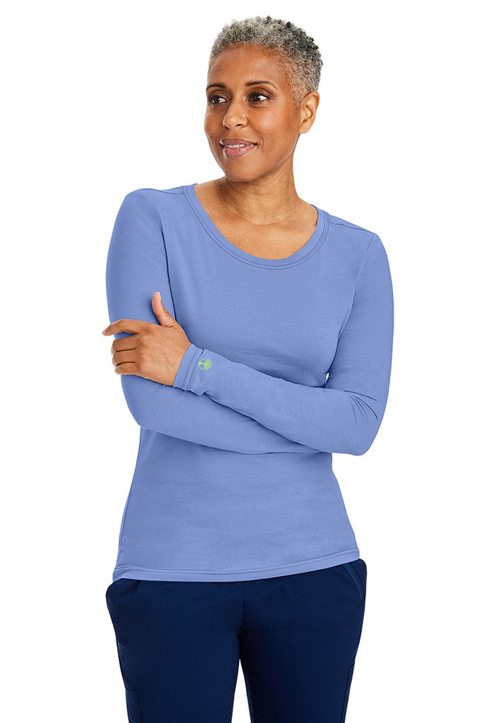 A female LPN wearing a Women's Melissa Long Sleeve T-Shirt from Purple Label by Healing Hands in Ceil featuring long sleeves with banded cuffs.