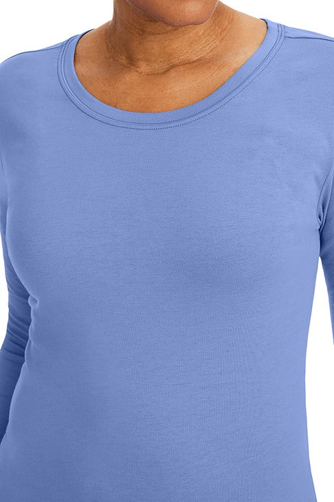 A lady nurse practitioner wearing a Purple Label Women's Melissa Long Sleeve T-Shirt from Healing Hands in Ceil featuring a super comfortable fabric blend that resists wrinkles, shrinking, and fading better than traditional cotton scrubs.