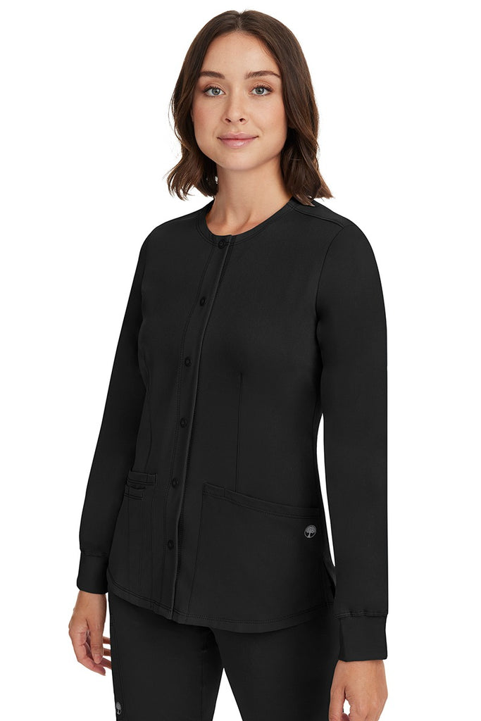 A young female CNA wearing an HH-Works Women's Megan Snap Front Scrub Jacket in Black featuring side slits for additional range of motion.