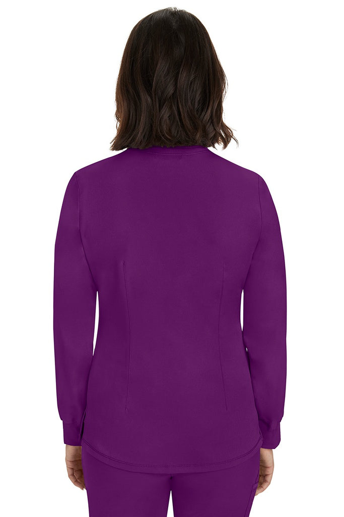 A young female Home Care Registered Nurse wearing an HH-Works Women's Megan Snap Front Scrub Jacket in Eggplant featuring a medium center back length of 25.5".