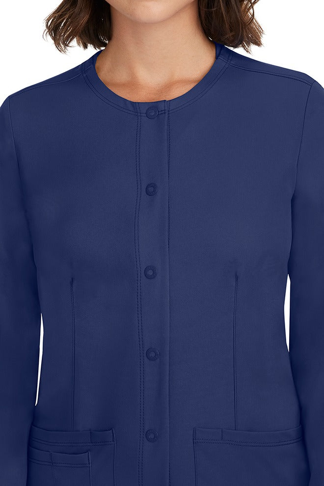 A female LPN wearing a Women's Megan Snap Front Scrub Jacket from HH Works in Navy featuring a snap-up button front closure.