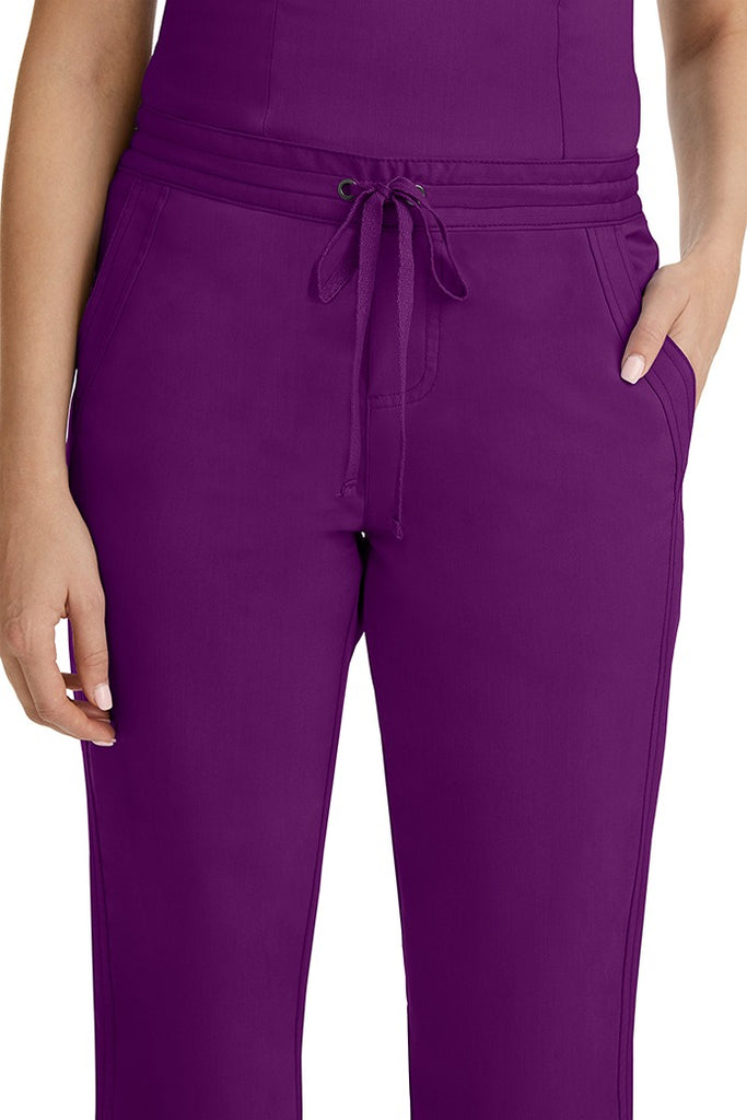 A female healthcare professional wearing a Purple Label Women's Taylor Drawstring Scrub Pant in Eggplant featuring triple needle stitching throughout.