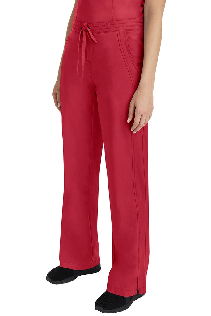 A young Home Care Registered Nurse wearing a Purple Label Women's Taylor Drawstring Scrub Pant in Red featuring front wrap seaming detail throughout.