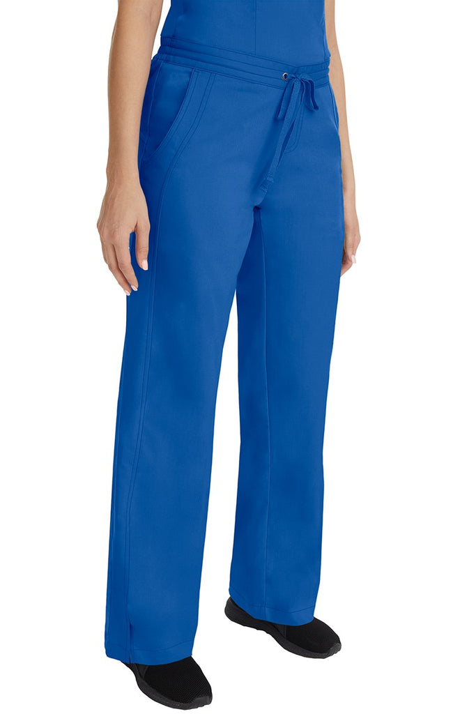 A young female RN wearing the Purple Label Women's Taylor Drawstring Scrub Pant in Royal featuring side slits at the ankle for easy slip-on or removal.