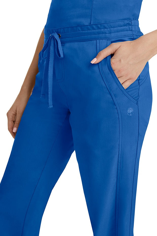A young woman wearing a pair of Purple Label Women's Taylor Drawstring Scrub Pants from Healing Hands in Royal. Perfect for Healthcare Professionals working in Hospitals, Doctors offices, Dental Groups & Veterinary offices!