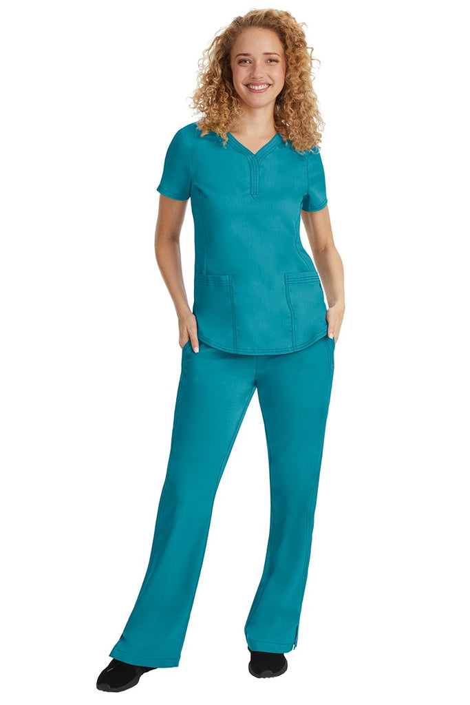 A young female nurse wearing a Purple Label Women's Taylor Drawstring Scrub Pant from Healing Hands in Teal featuring a fabric that resists wrinkles, shrinking & fading better than traditional cotton scrubs.