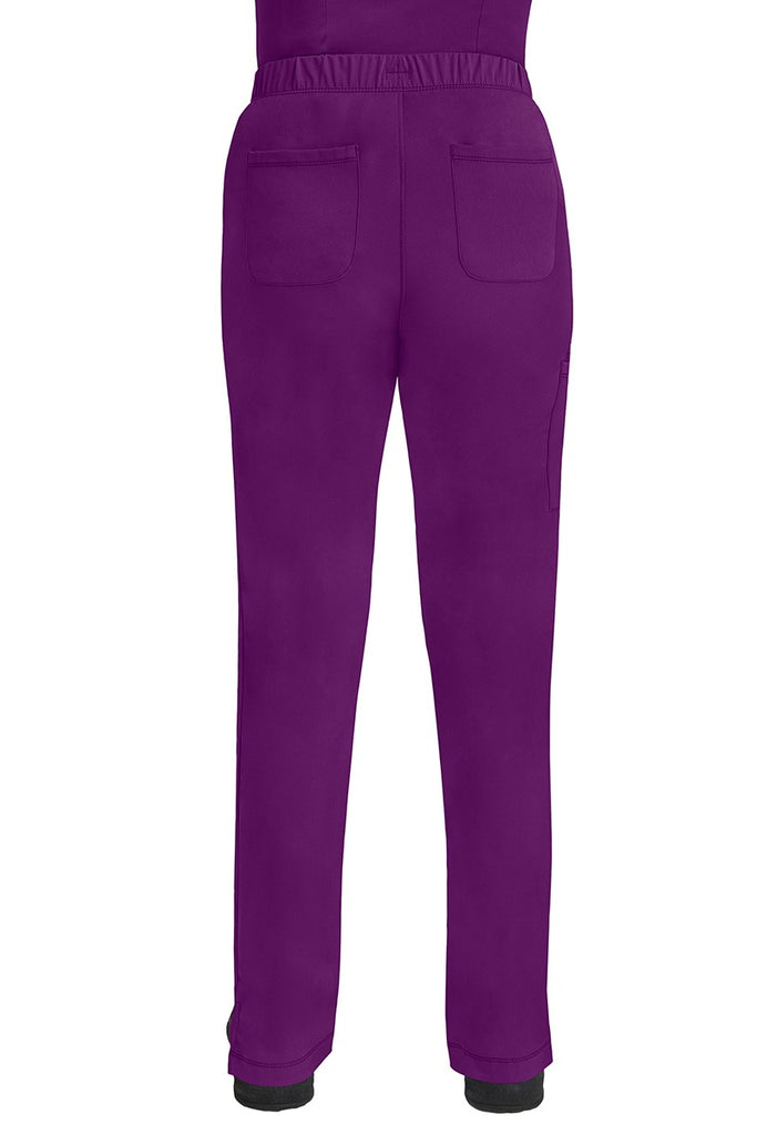 A lady CNA wearing an HH-Works Women's Rebecca Multi-Pocket Drawstring Pant in Eggplant featuring 2 back patch pockets for any additional on the job storage needs.