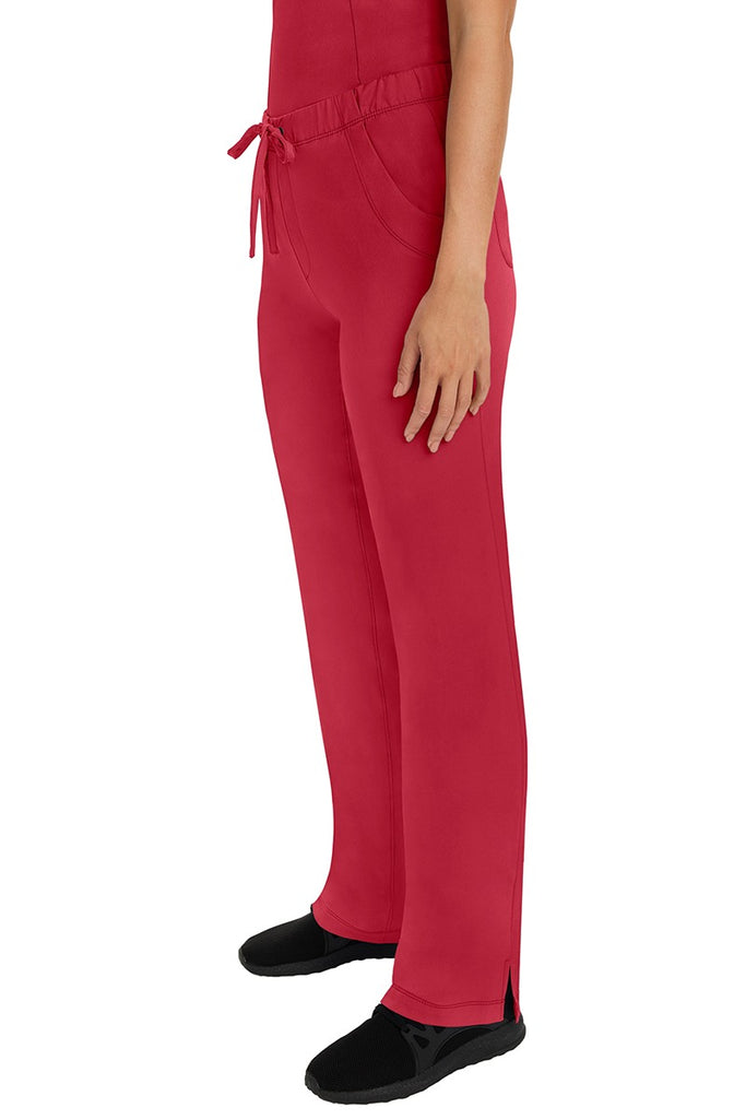 A woman Home Care Registered Nurse wearing a pair of HH-Works Women's Rebecca Multi-Pocket Drawstring Pants in Red featuring side slits for additional range of motion.