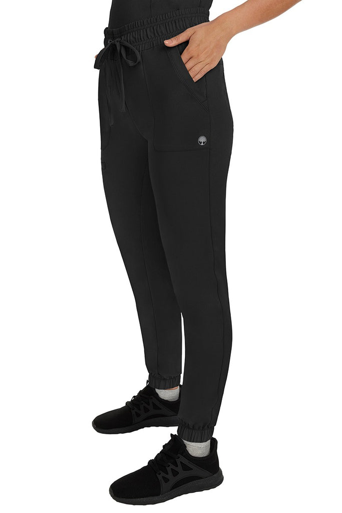 A female healthcare professional wearing a pair of the HH Works Women's Renee Jogger Scrub Pants in Black featuring stretchy ankle cuffs at the bottom of each pant leg.