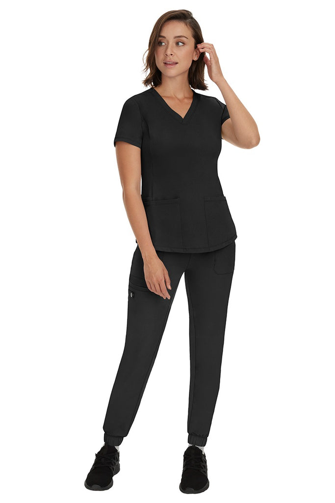 A young female RN wearing an HH Works Women's Renee Jogger Scrub Pant in Black featuring a modern fit with an elastic waist.