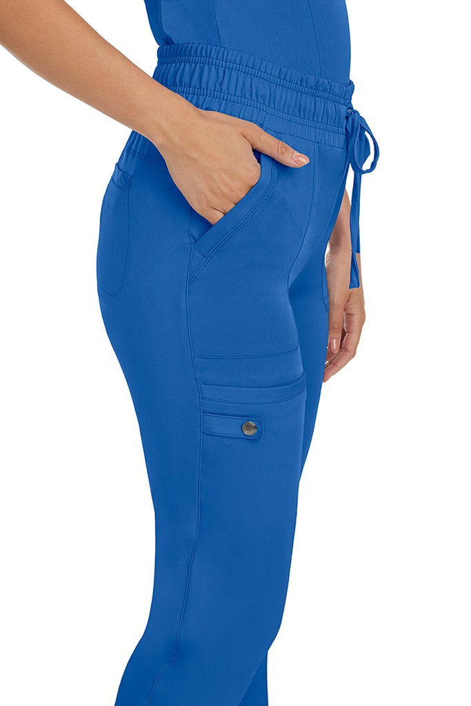 A female nurse wearing a pair of the HH Works Women's Renee Jogger Scrub Pants in Royal featuring a total of 6 pockets for all of your on the go storage needs.