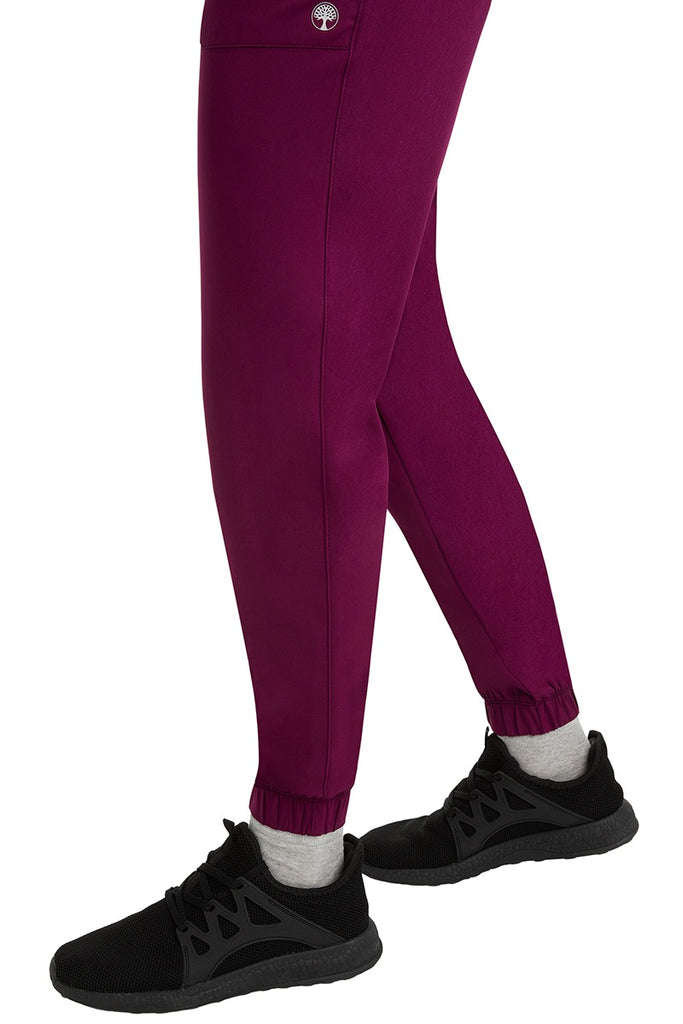A female healthcare professional wearing a pair of the HH Works Women's Renee Jogger Scrub Pants in Wine featuring stretchy ankle cuffs at the bottom of each pant leg.