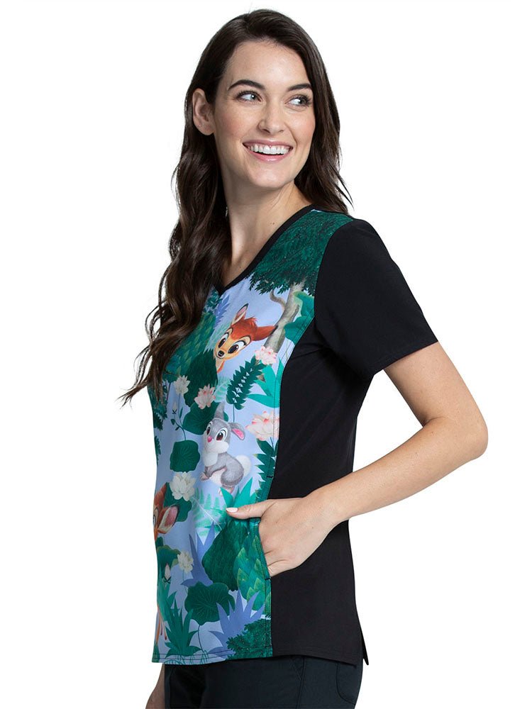 A young female Psychiatric Nurse wearing a Tooniforms Women's V-Neck Printed Scrub Top in "Forest Frolic" featuring 2 front in-seam slip pockets.