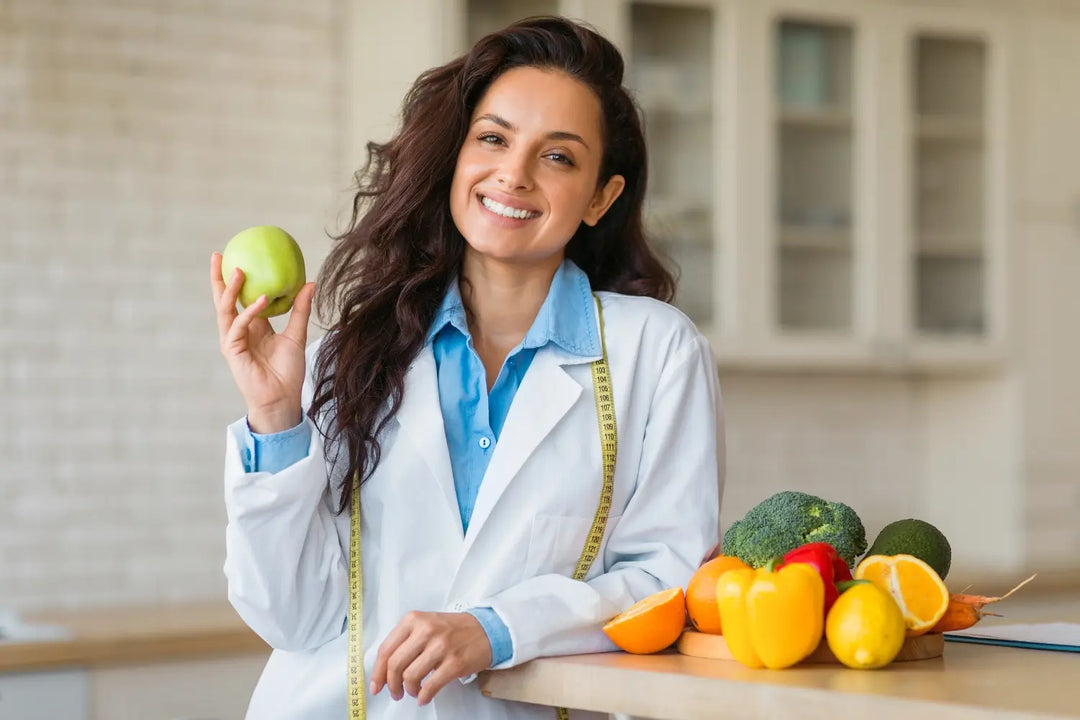 Doctor holding an apple next to furits and vegetables.