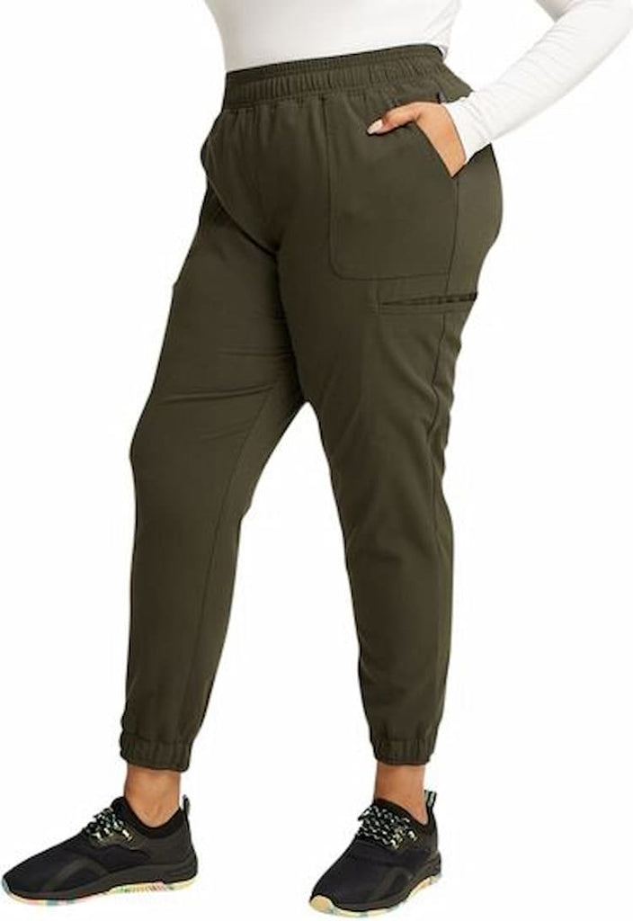 A young female Cardiologist wearing a pair of Vince Camuto Women's Mid Rise Scrub joggers in Heathered Olive size Medium Petite featuring a 29" inseam.