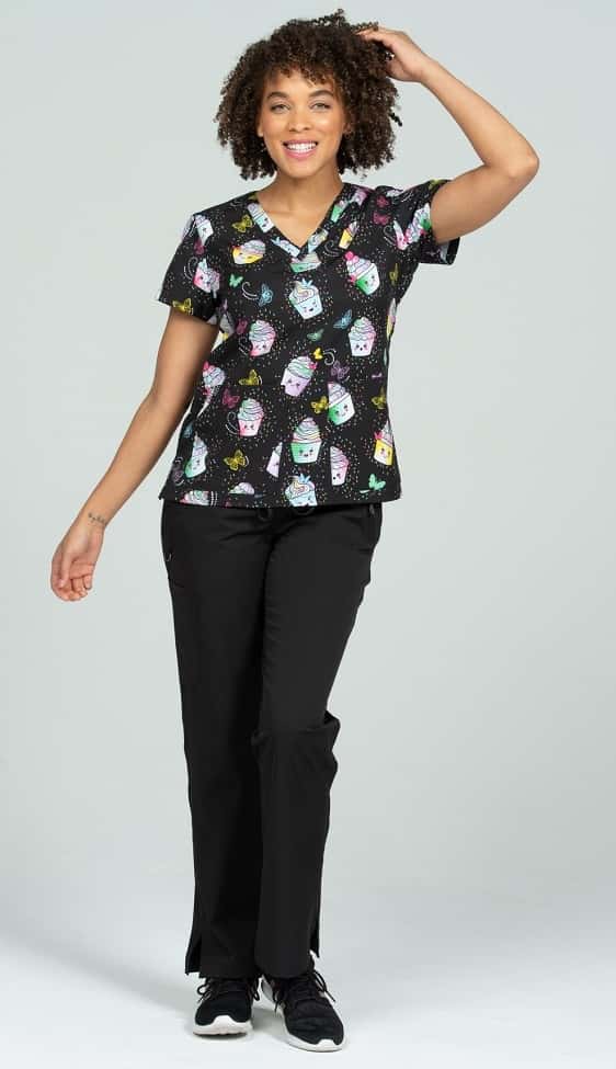 A female LPN wearing a Women's Print Scrub Top from Meraki Sport in "Cake It Easy" size Small featuring 2 front patch pockets & shoulder yokes for a flattering shape.