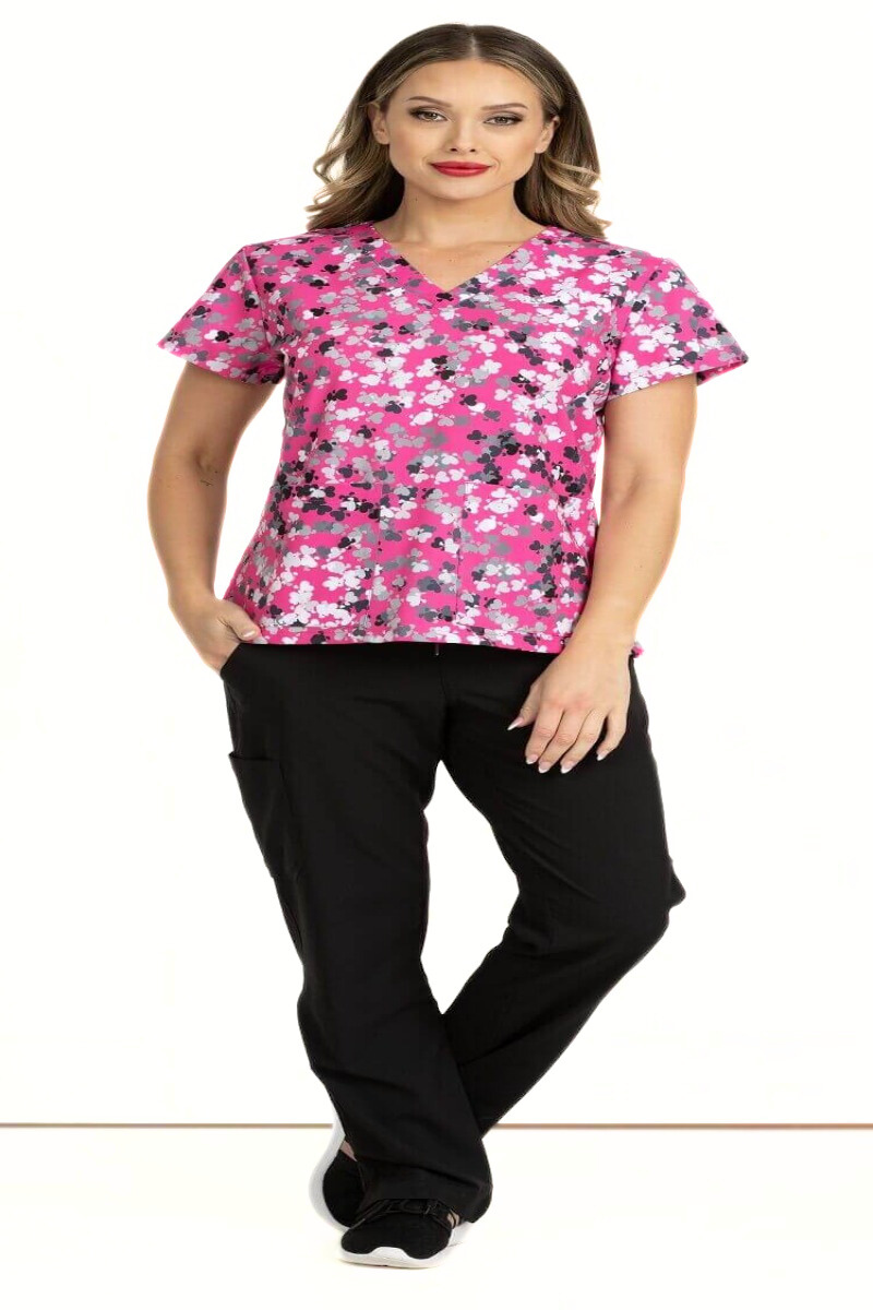 A full body image of a female LPN wearing a Women's Print Scrub Top from Meraki Sport in "Love Crushin" size Small featuring 2 front patch pockets & shoulder yokes for a flattering shape.