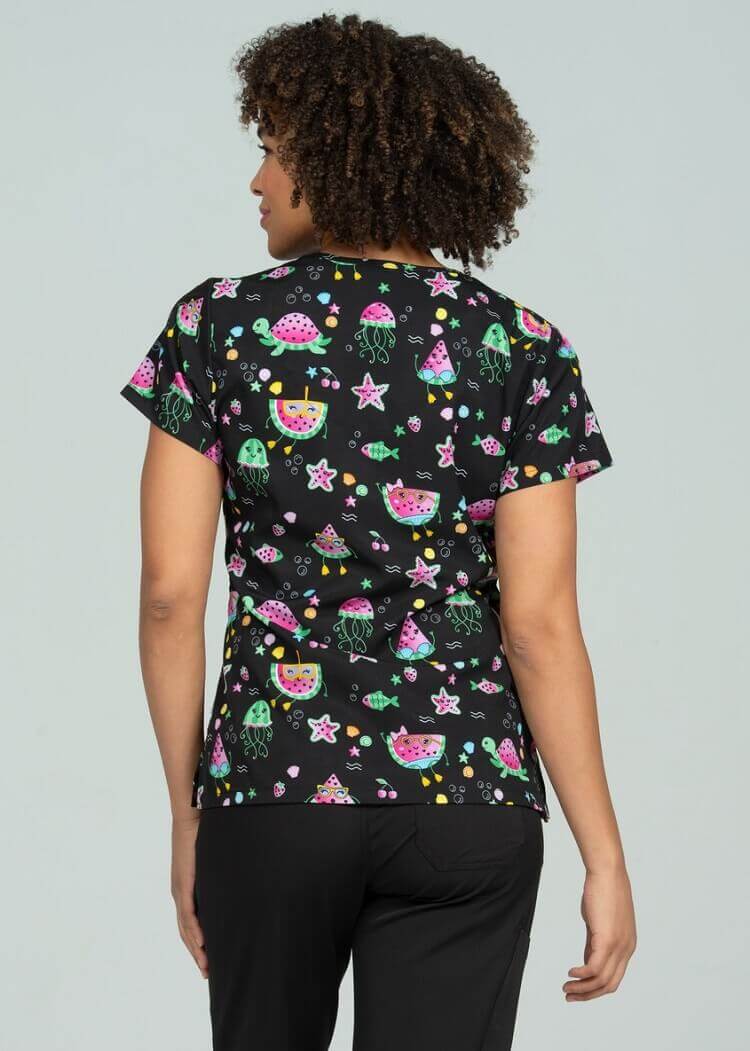 A young female Phlebotomist wearing a Meraki Sport Women's Print Scrub Top in "One in a Melon" size 2XL featuring shoulder yokes & side slits for additional range of motion.