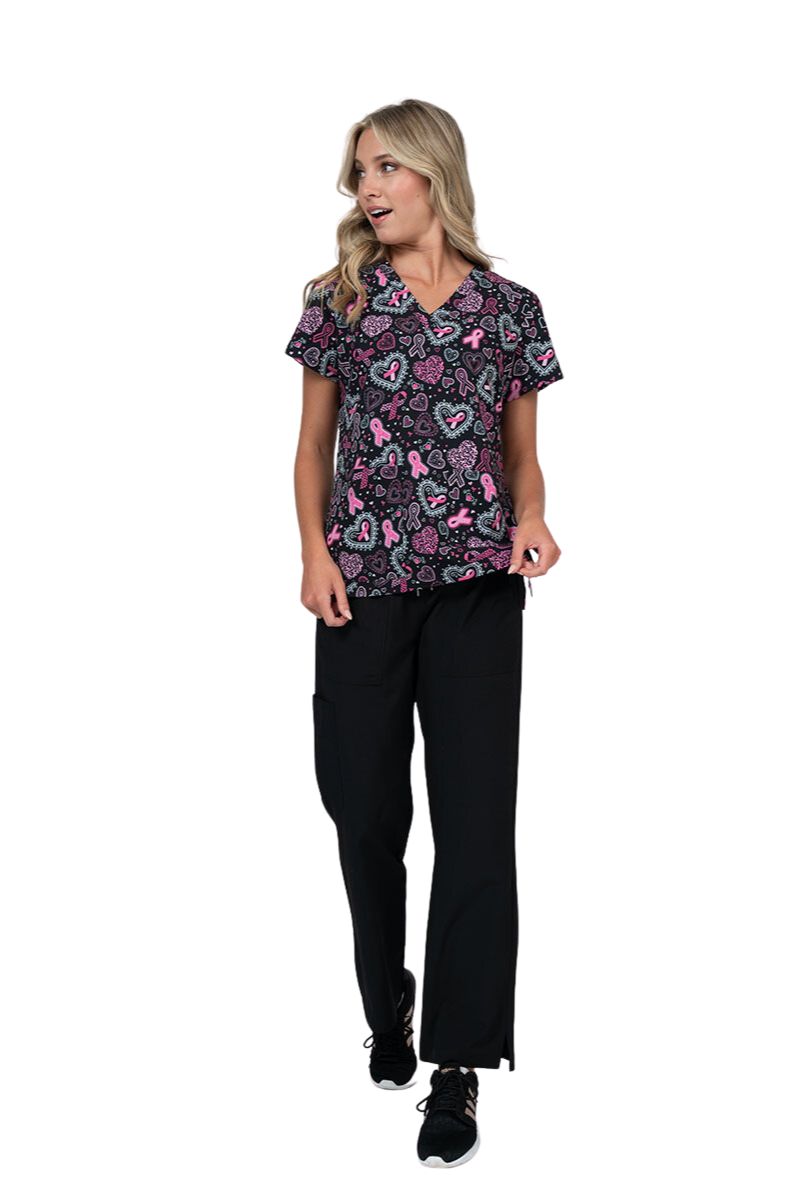 A frontward facing shot of a young female Nurse wearing a Meraki Sport Women's Breast Cancer Awareness Printed Scrub Top in "Pink Strength" featuring a unique 4-way movement stretch fabric.