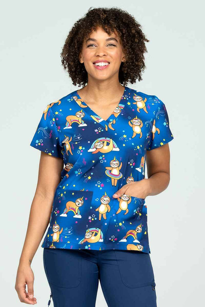 A young female Pharmacy Technician wearing a Meraki Sport Women's Print Scrub Top in "Sloth Squad" featuring 2 front patch pockets side slits for increased range of mobility.