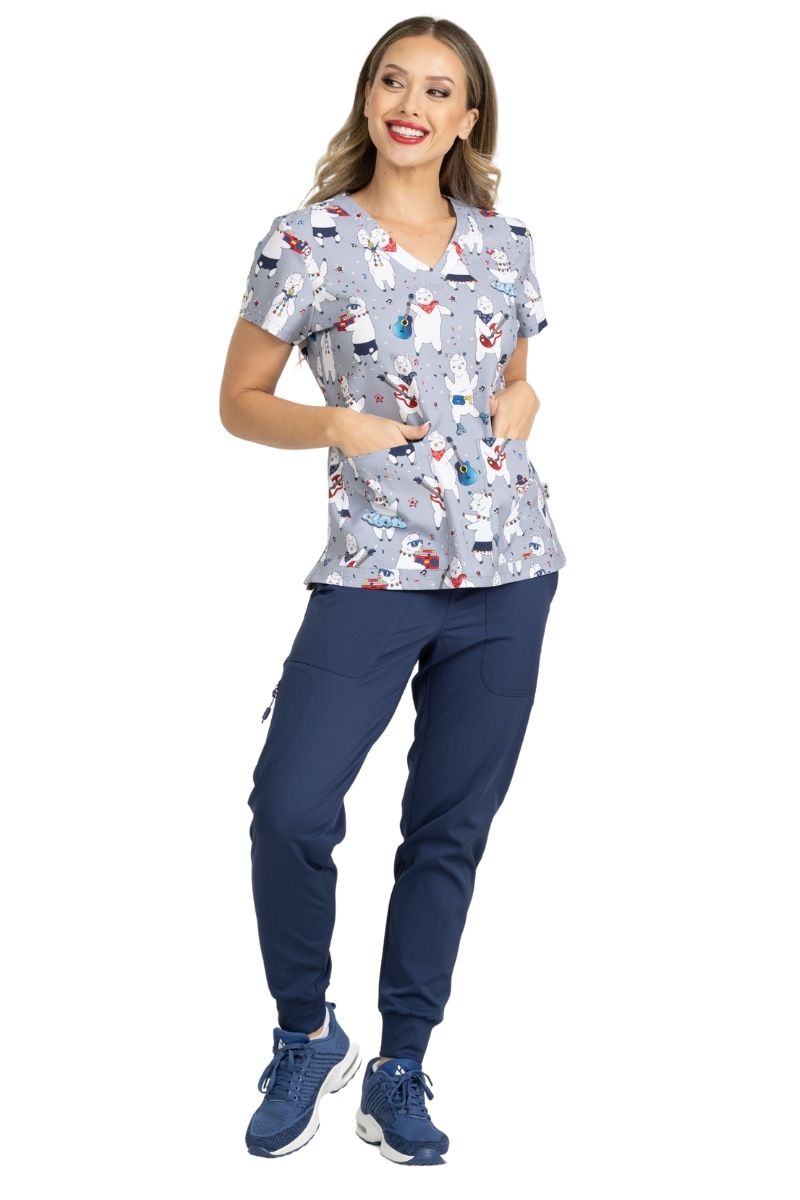 A young female Pediatric Nurse showcasing the Llamazing Print Scrub Top from Meraki Sport by MedWorks featuring two front patch pockets.