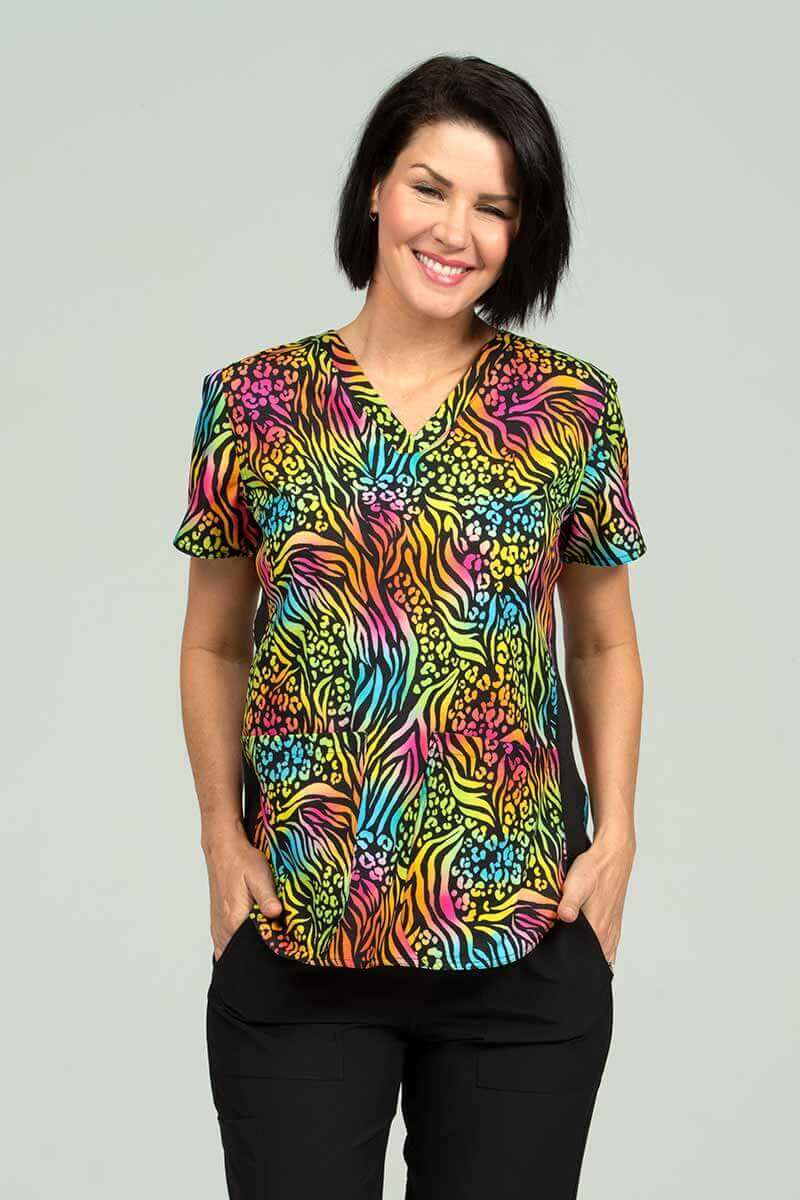 A young female Pediatrician wearing a Meraki Sport Women's Print Scrub Top in "Bold Moves" size Medium featuring a contemporary fit with a V-Neckline.