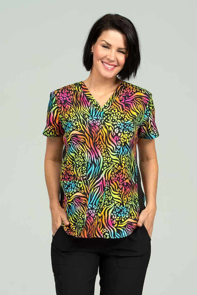 A young female Pediatrician wearing a Meraki Sport Women's Print Scrub Top in "Bold Moves" size Medium featuring a contemporary fit with a V-Neckline.