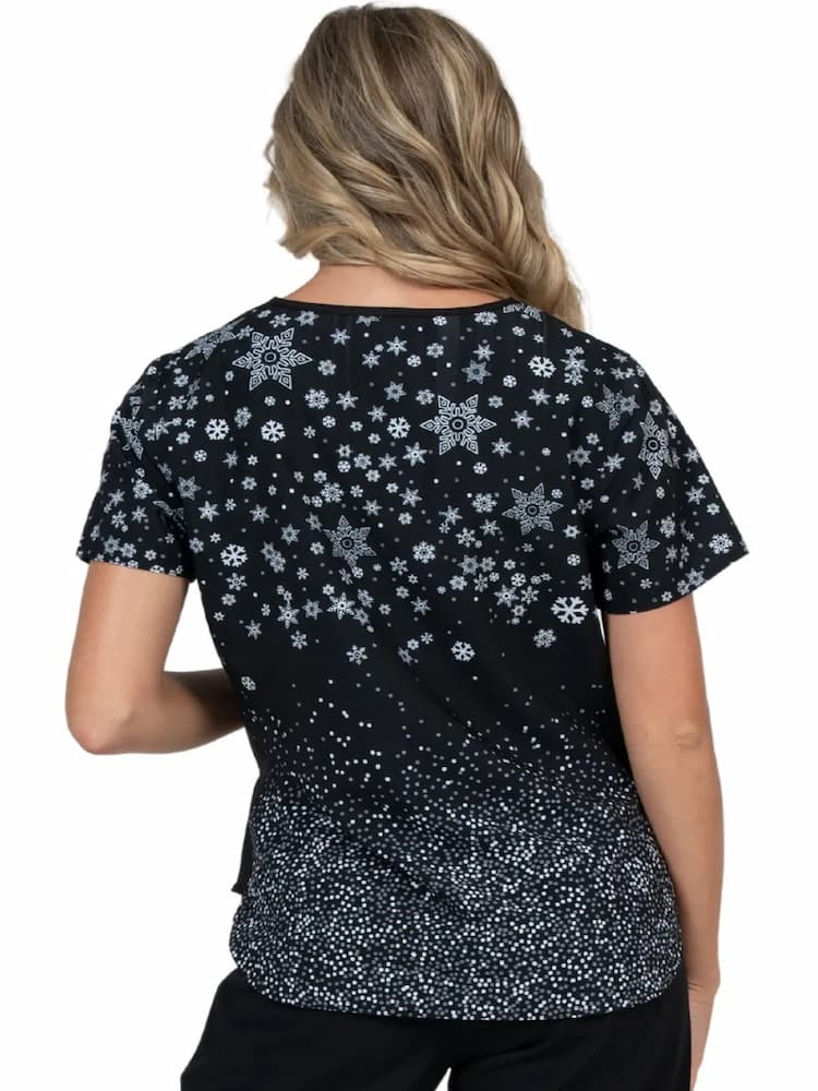 An image of the back of a young female RN wearing a Meraki Sport Women's Print Scrub Top in "Winter Vibes" featuring back and shoulder yokes. 