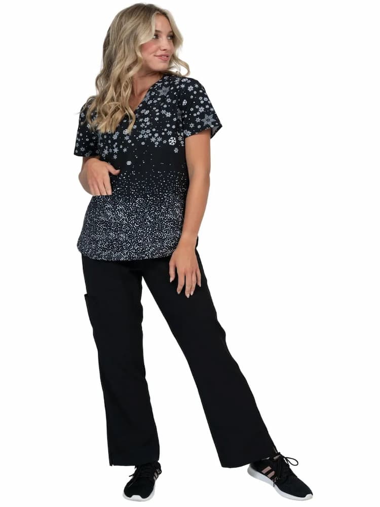 A full body image of a LPN wearing a Meraki Sport Print Scrub Top in Winter Vibes size medium.