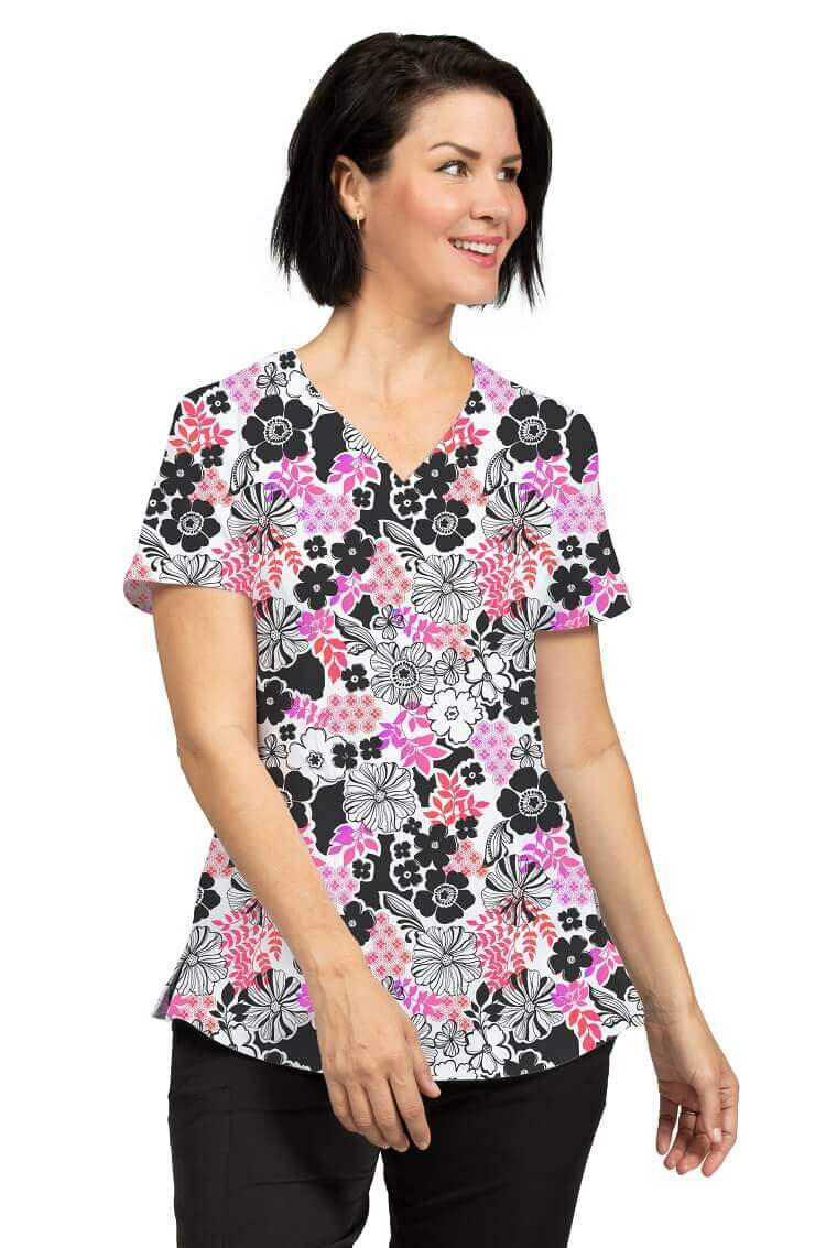 A young female Veterinarian wearing a Meraki Sport Women's Print Scrub Top in "Flowerista" size Medium featuring 2 front patch patch pockets & a V-neckline.