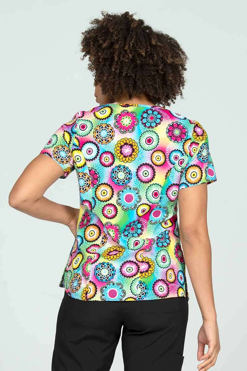 A young female Family Practitioner wearing a Meraki Sport Women's Print Scrub Top in "Pop of Fun" featuring front & back princess seaming to ensure a flattering fit.