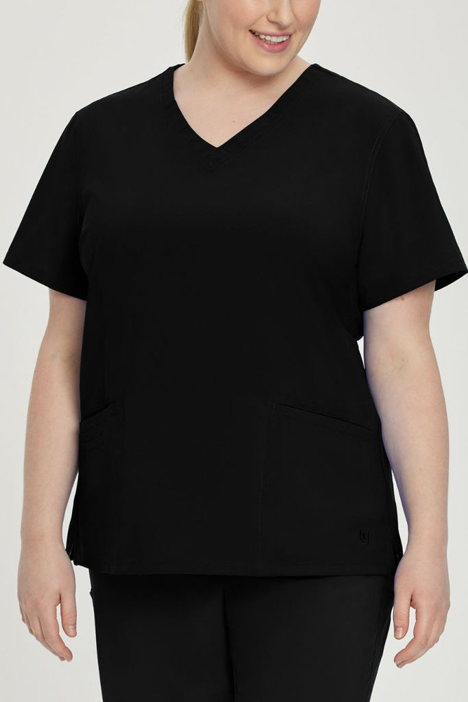 A young female EMT wearing an Urbane Performance Women's Motivate V-neck Scrub Top in Black size 2XL featuring tonal stitching and bust darts.