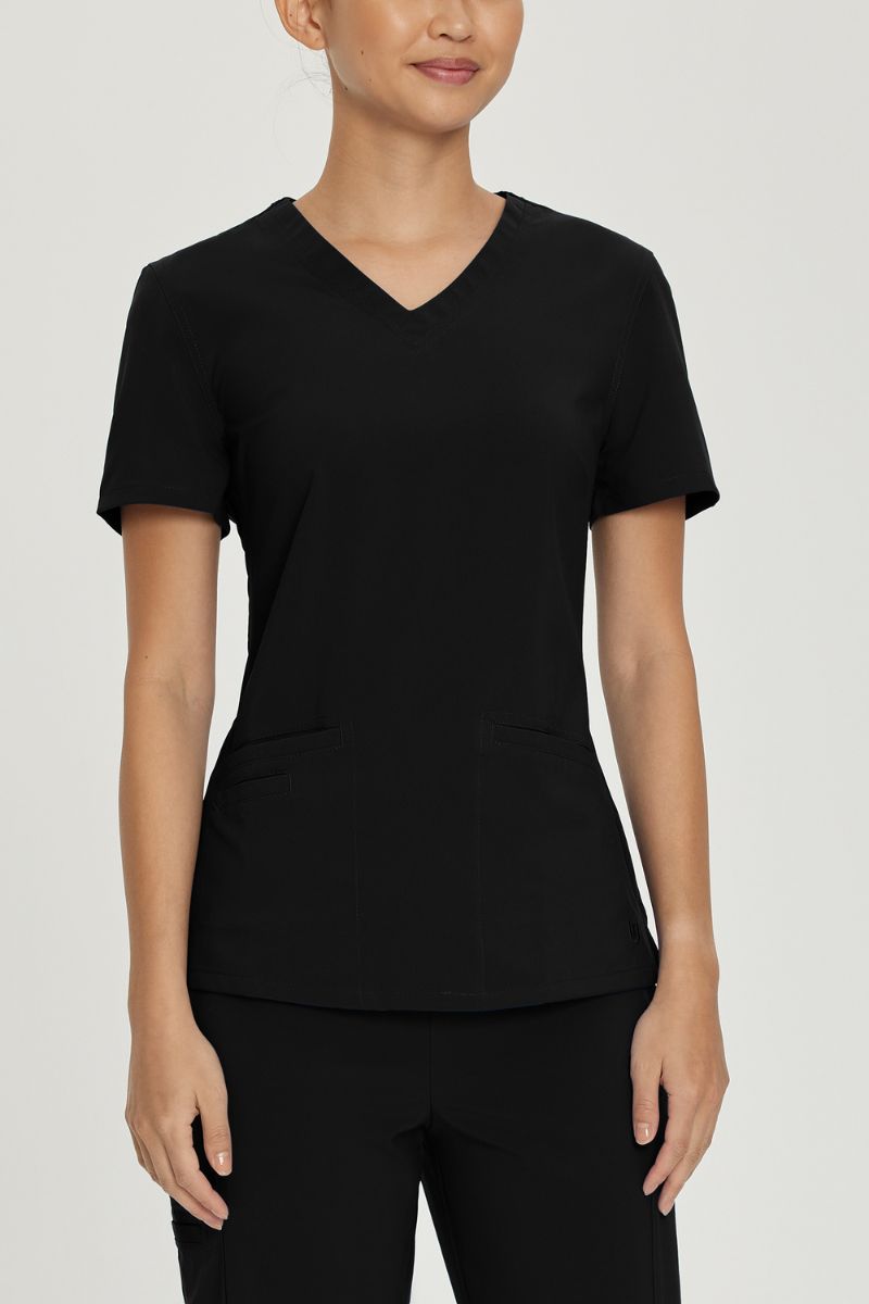 A young female LPN wearing an Urbane Performance Women's Motivate V-neck Scrub Top in Black size XS featuring a unique, 4-way stretch fabric.